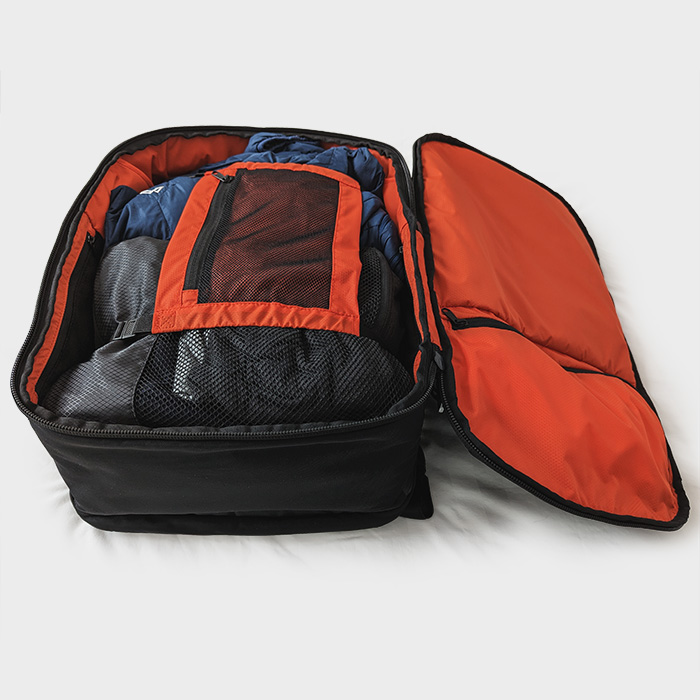 Open backpack, main compartment on the bed, showing packed items